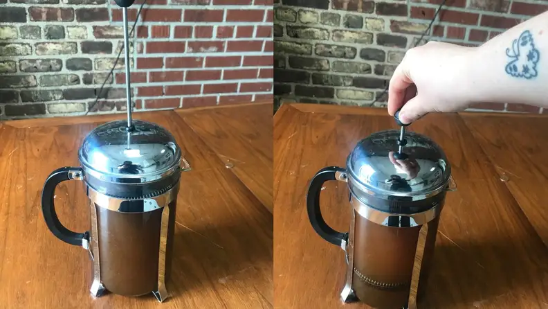 A person pushes the plunger on a French press coffee maker to make cold brew coffee.