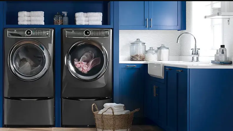 The Electrolux EFME627UTT dryer and an Electrolux washer standing side by side in a blue laundry room.