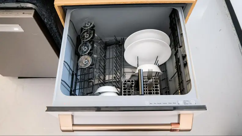 A close-up of the dishwasher's top drawer, which has a rack and a few plates, bowls, and wine glasses stowed.