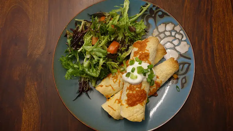 Beef and Corn Taquitos with Chopped Salad on a grey plate viewed from above.