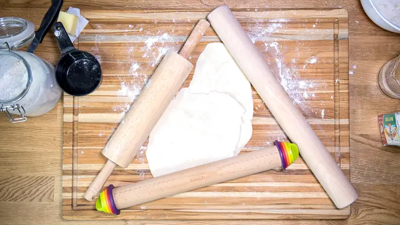 Three rolling pins next to flour and baking ingredients