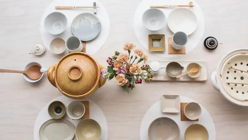 A top-down photo of a set table with a donabe clay pot in the center.