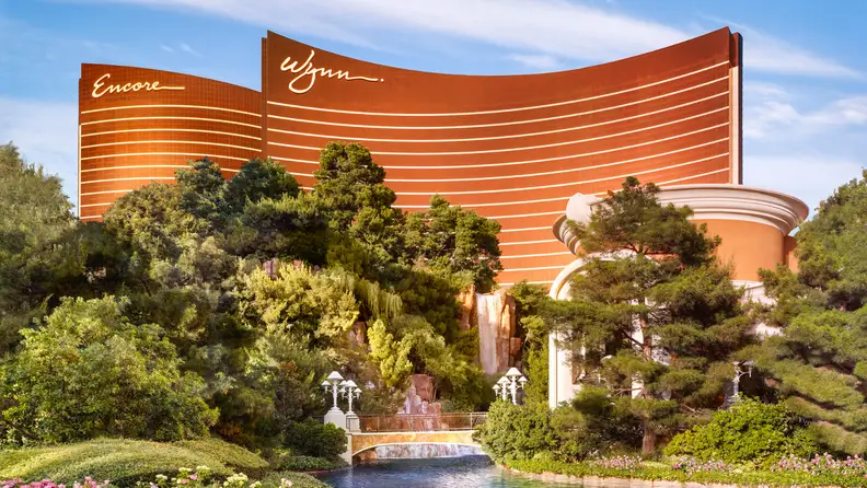 Wynn Las Vegas and Encore resort towers rising above lush gardens, waterfalls, and landscaped grounds on the Las Vegas Strip.