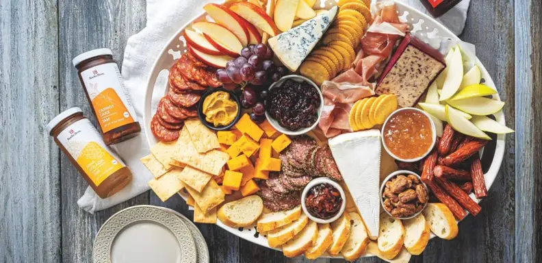 Charcuterie board with cheeses, meats, and jam jars