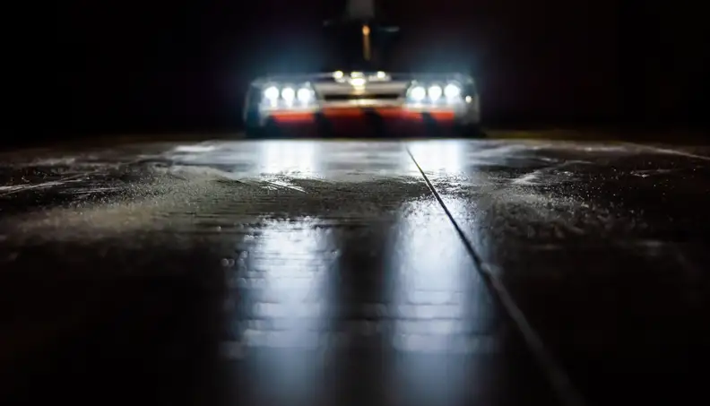 A vacuum with LED lights cleans the floor in a dark room