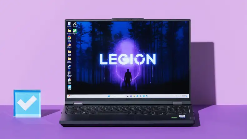 Black Lenovo Legion Pro 5i Gen 8 gaming laptop opened with desktop screensaver on screen next to blue acrylic paperweight in the middle of purple setting.