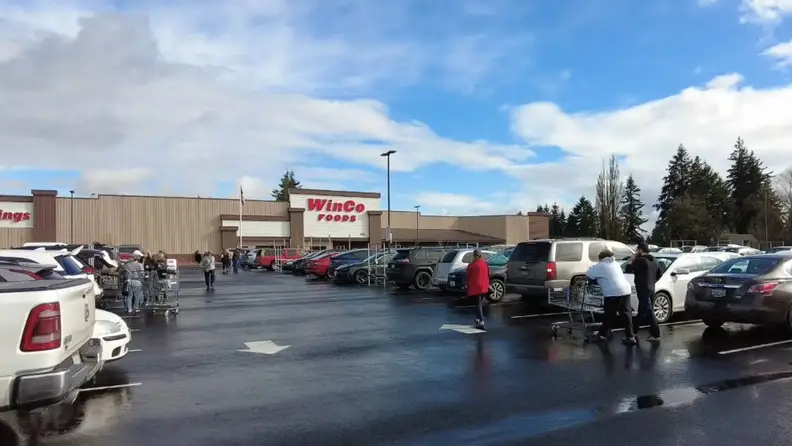 WinCo Foods parking lot with shoppers pushing carts to their cars