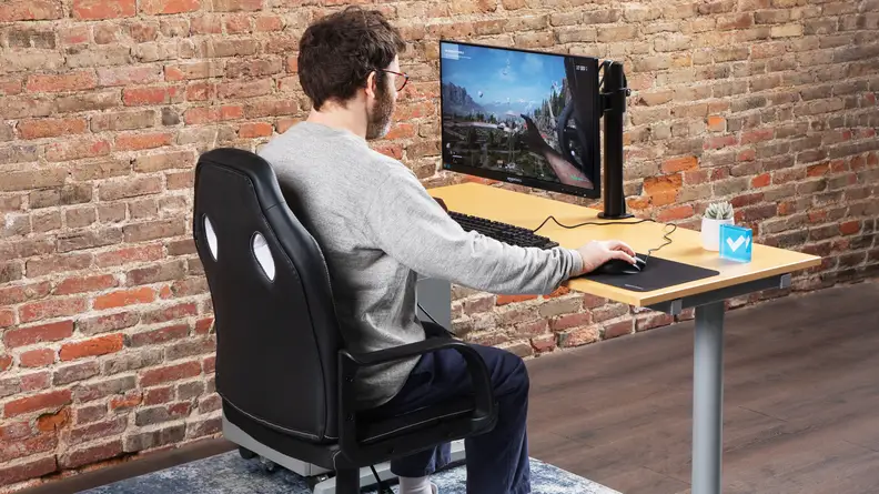 A person sitting on the Amazon Basics Racing/Gaming style office chair using a computer on a monitor.