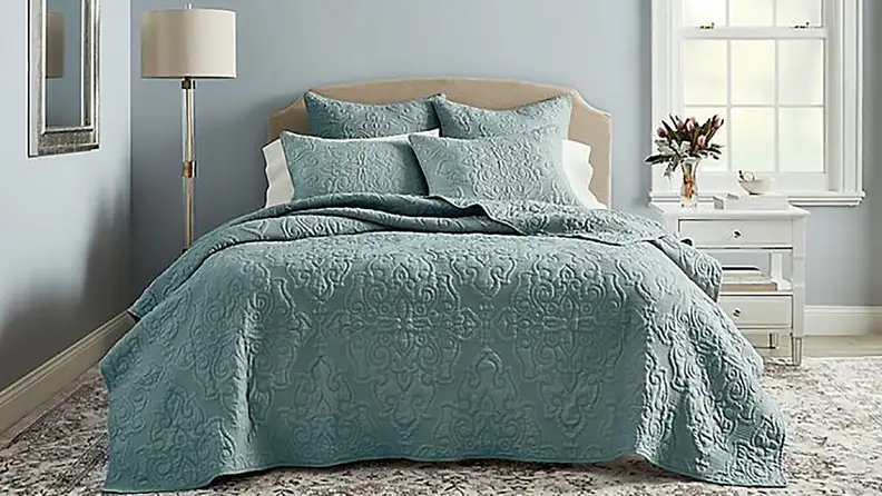 Bed with teal comforter set in bedroom.
