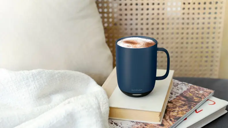 A Ember Temperature Control smart mug on top of some books in an indoor setting.