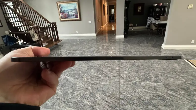 Side shot of a person holding up the iPad Pro, showing how thin it is.