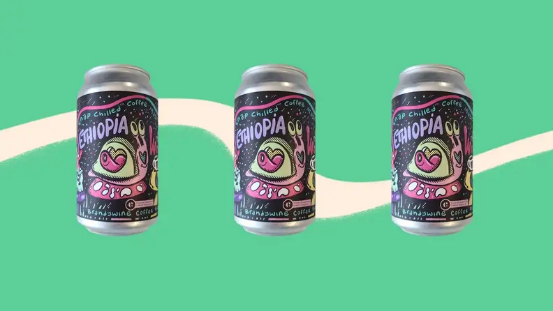 Three cans of coffee arranged in a straight line on a green background.