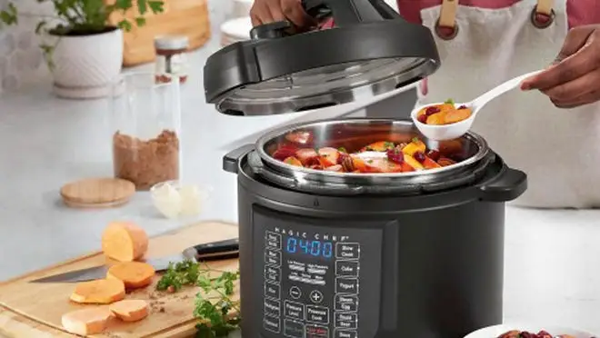 A person takes a spoonful of food out of a slow cooker.