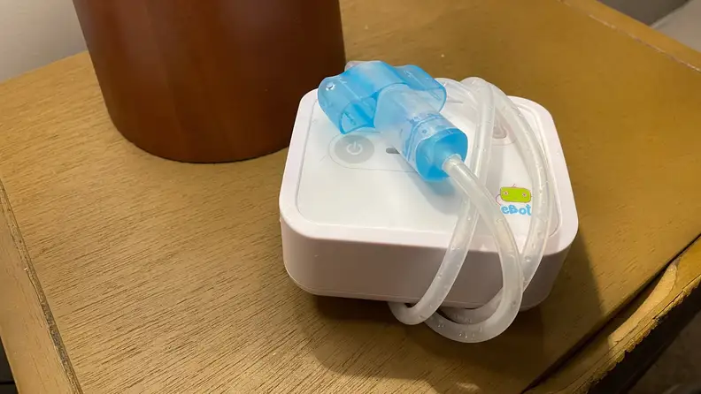 A Nozebot suction device with its tube wrapped around it.