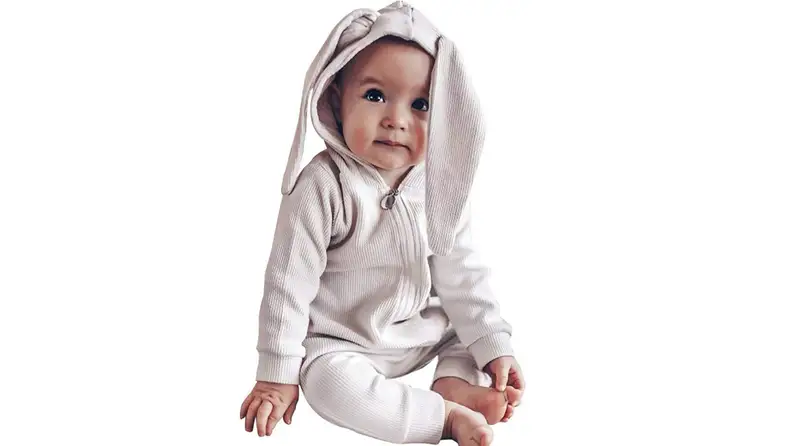 An adorable child in a bunny-eared romper