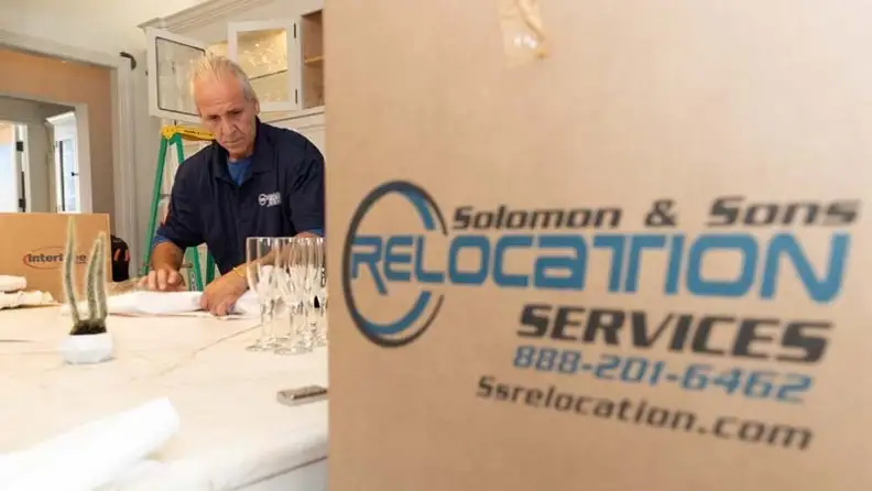 A mover carefully packing drinkware before boxing