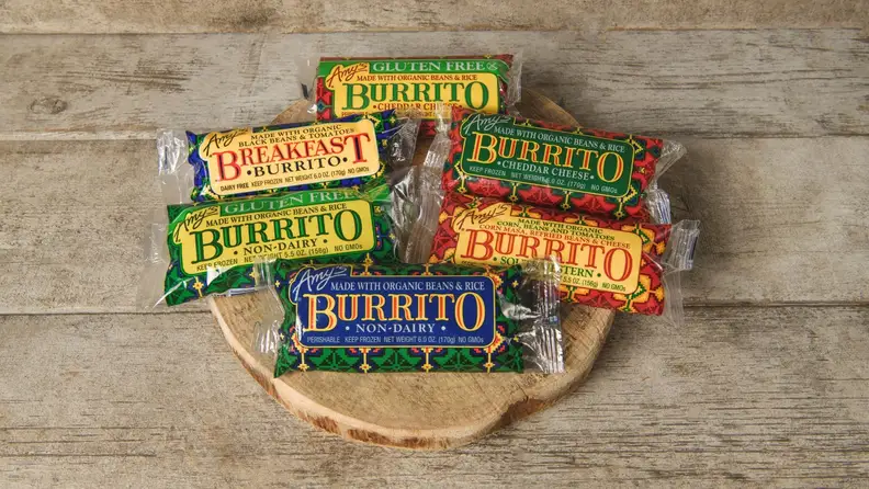 Assortment of Amy's Kitchen frozen burrito packages on a wood board