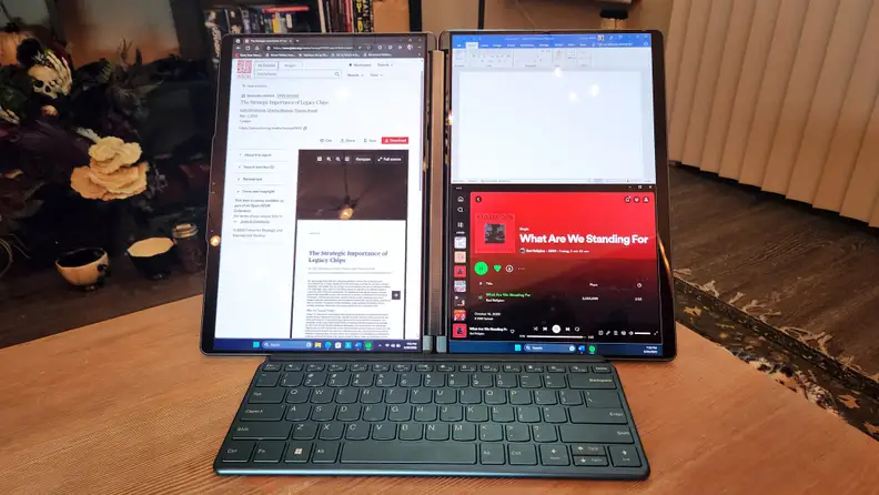 A dual-screen laptop propped up with a small keyboard in front.