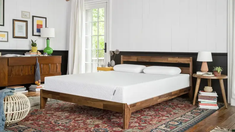 Bare memory foam mattress in frame in bedroom.