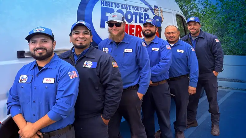 Team of six technicians posing in front of a service van