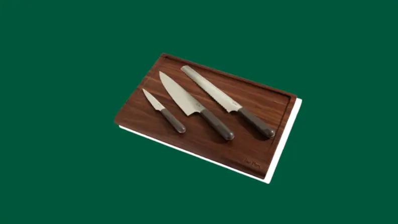 Three knives on a wooden cutting board, on a green background