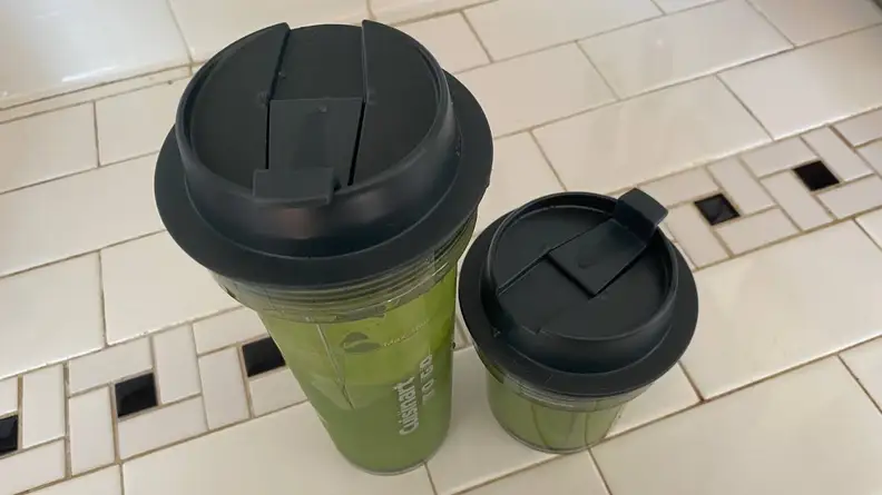 Two different sized Cuisinart travel mugs with lids and green smoothies inside side by side.