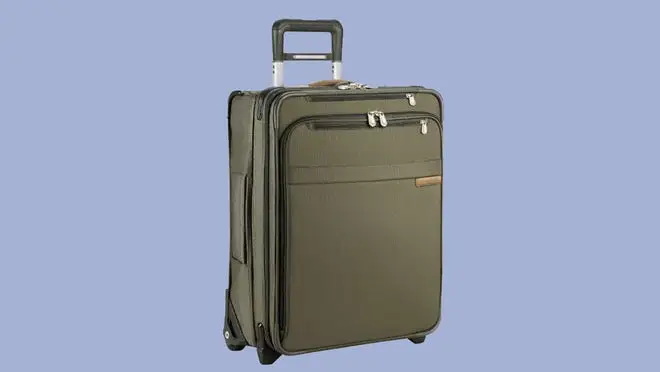 Olive green Briggs & Riley carry-on rolling suitcase in front of purple background.
