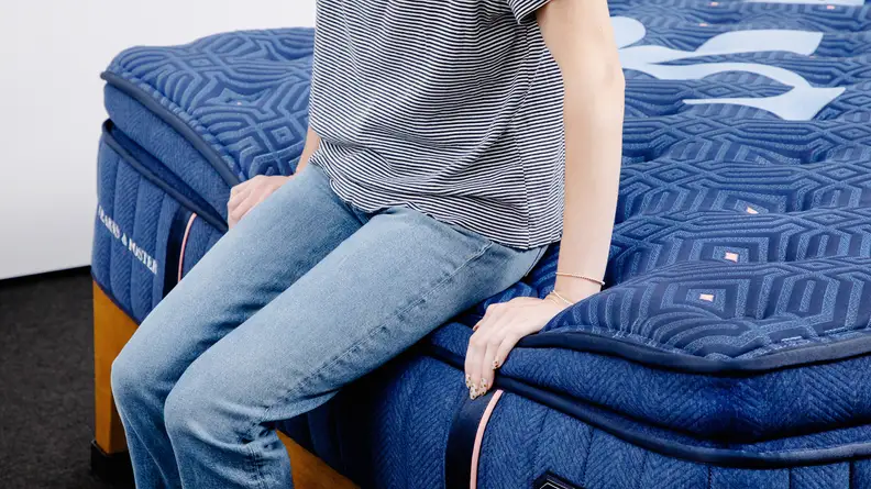 A person sitting on the edge of the Stearns & Foster mattress.