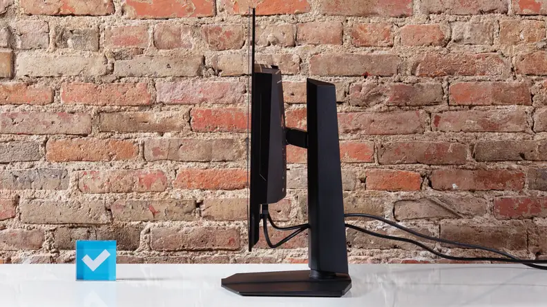 A side view of the MSI MPG 321URX computer on a white desktop with a brick background.