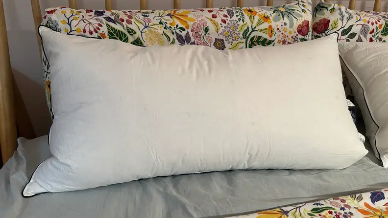 White Pacific Coast Feather & Down Pillow on a bed with floral and grey sheets.