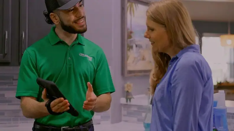 Technician holding a tablet while talking with a customer indoors
