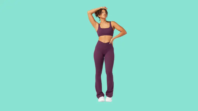 A model wearing a sports bra and matching flared exercise pants in plum.