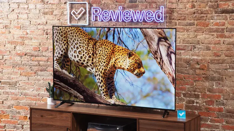 The TCL S4 LED TV on a wood entertainment center with a brick background.