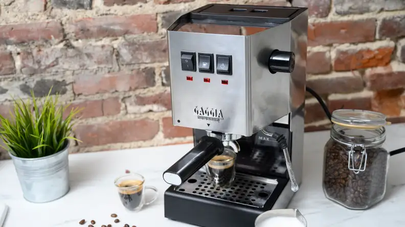 The Gaggia Classic Pro on a white countertop along with esspresso shots and coffee beans.
