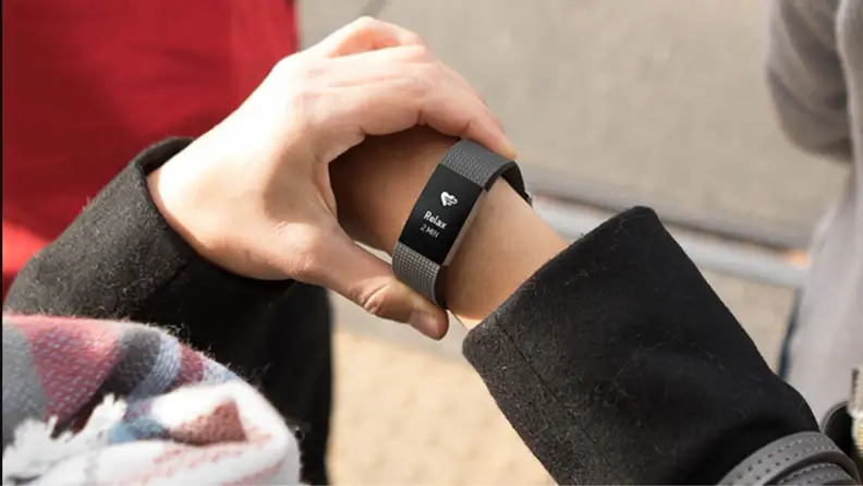 a woman's wrist shows the Fitbit Charge displaying the relax feature