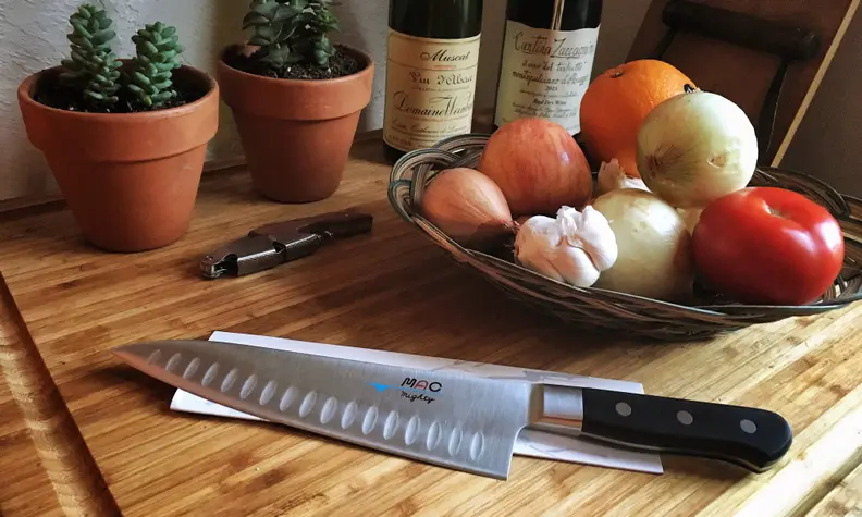 A knife sitting on a table next to some fruit.