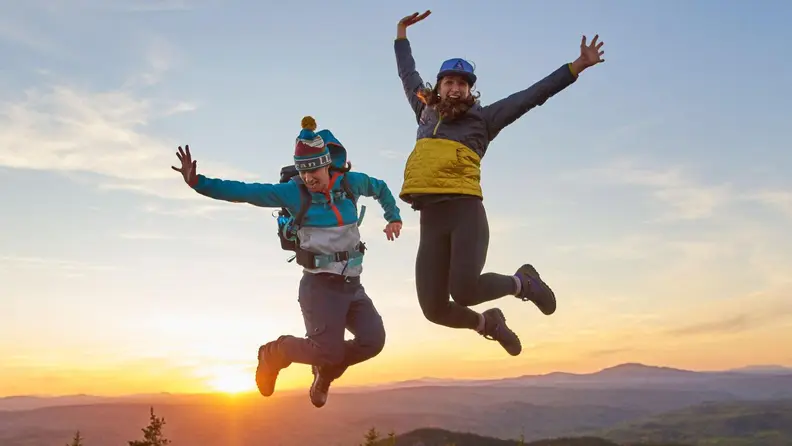 Two people jumping in L.L.Bean clothes on a mountain