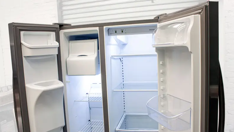 The Frigidaire FFSS2615TS side-by-side refrigerator with its right door open, stocked with groceries in the door compartments and main cavity.