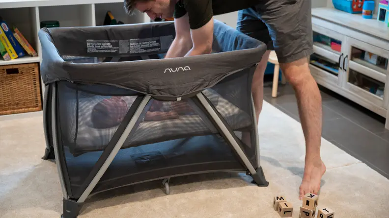 A dad putting his baby in a playard