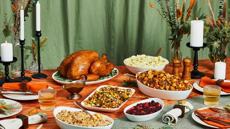 A Thanksgiving feast on an elaborately decorated table with sliced holiday turkey and various side dishes.