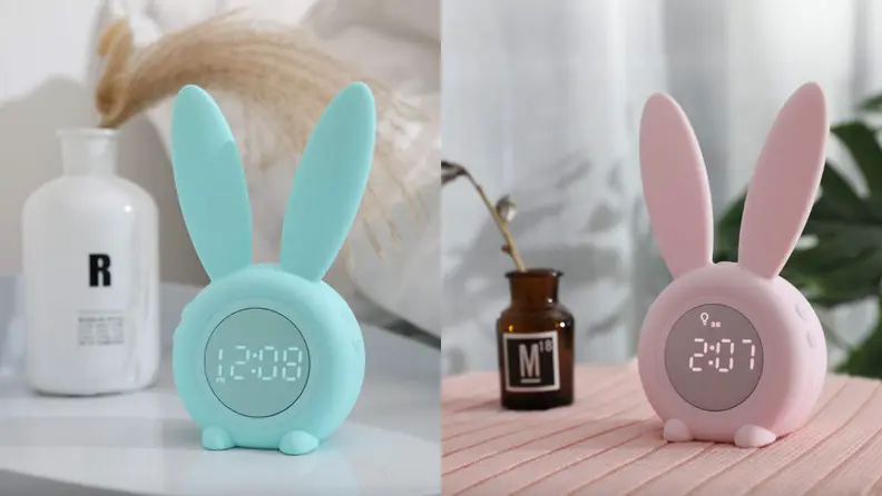 Bunny ear alarm clocks on pink blanket.