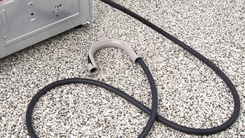 A close-up of a compact dryer's drainage hose. It's made of black rubber and ends in a gray plastic U-shaped piece.