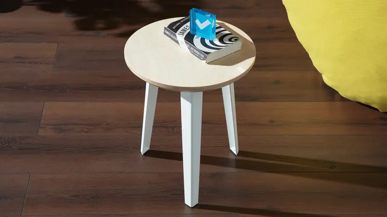 Product shot of the small side table from Floyd on top of wooden flooring next to the yellow Floyd Squishy Chair.