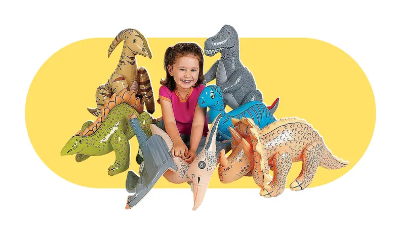 A little girl sitting next to a batch of giant inflatable dinosaurs.