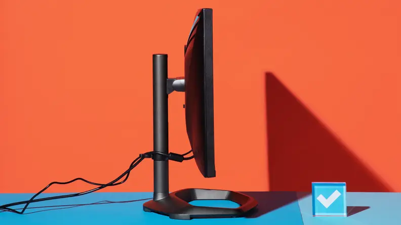 Side shot of the Cooler Master Tempest GP27Q gaming monitor on top of blue surface with wires coming out of back.