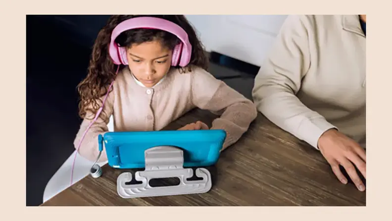 A young girl wearing headphones and looking at a tablet.