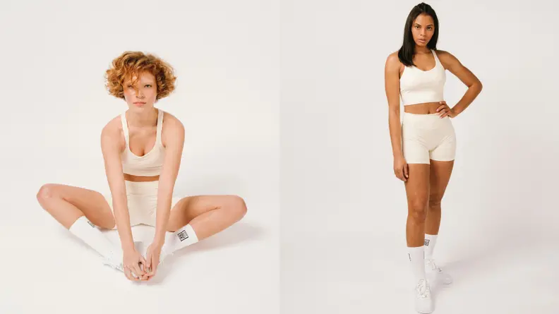 White woman wearing cropped biker shorts and athletic crop top.