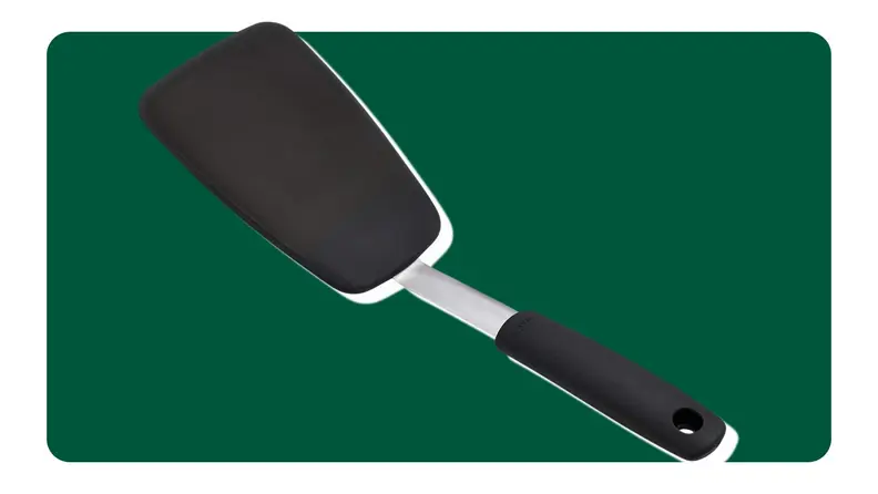 A black spatula on a green background