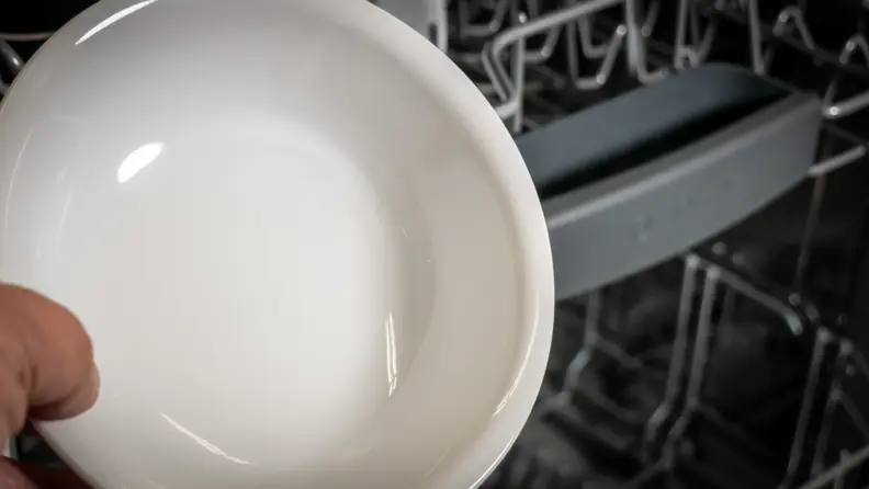 A close-up of a dish, which is spotless, in front of the Bosch 100 Series dishwasher.