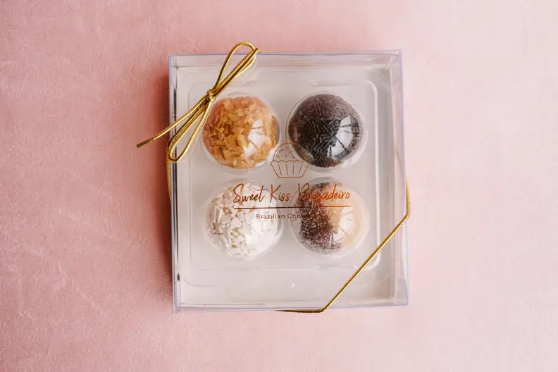 A box of eight assorted colorful Brazilian bon bons, covered in yellow, pink, brown, and white toppings.